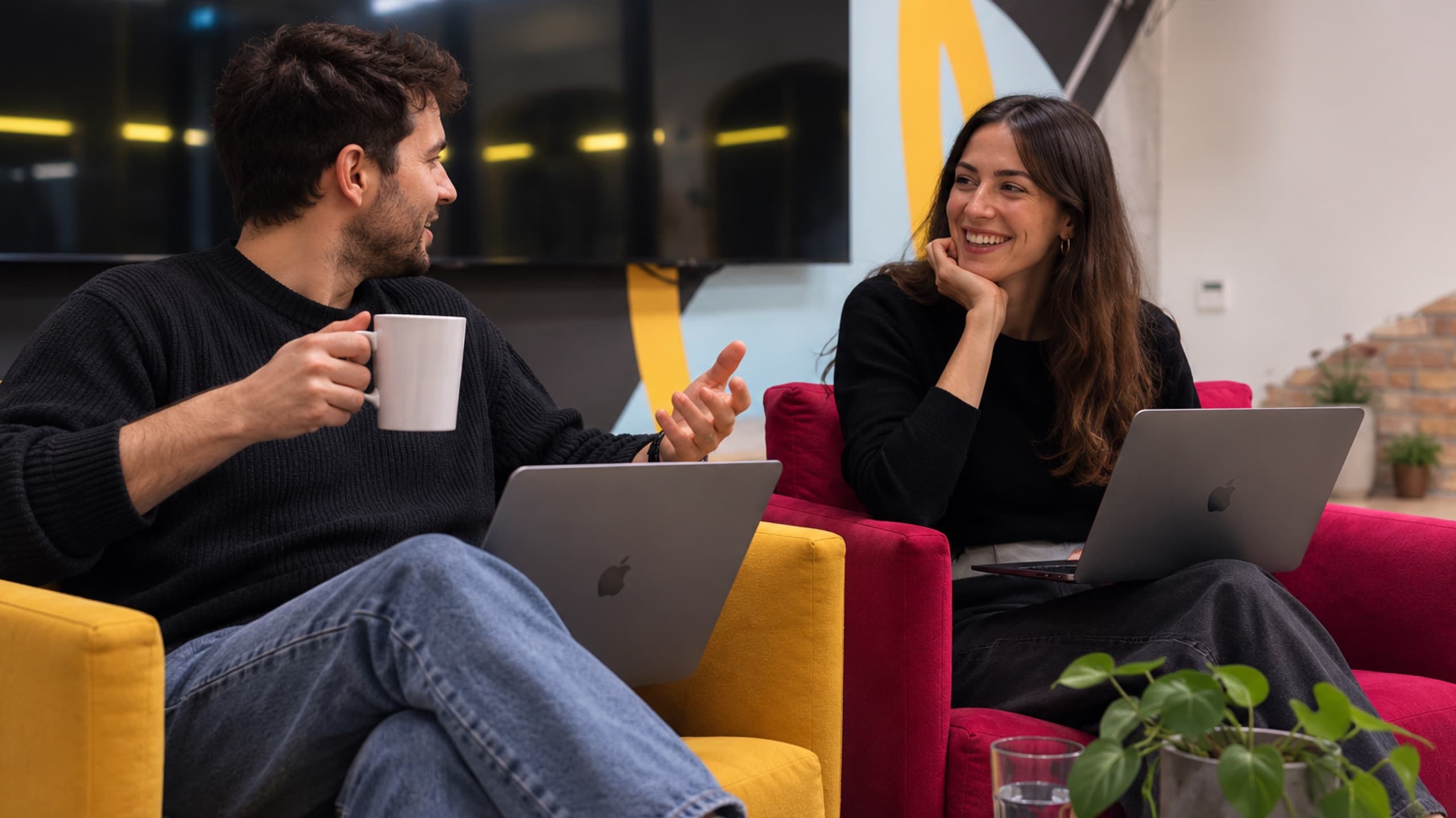 Two members talking over coffee and laptops in the tershouse lounge armchairs